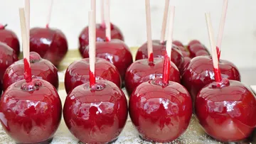 Rote Kandierte Äpfel mit Stielen auf Tablett.