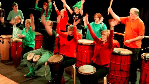 People drumming enthusiastically on stage.