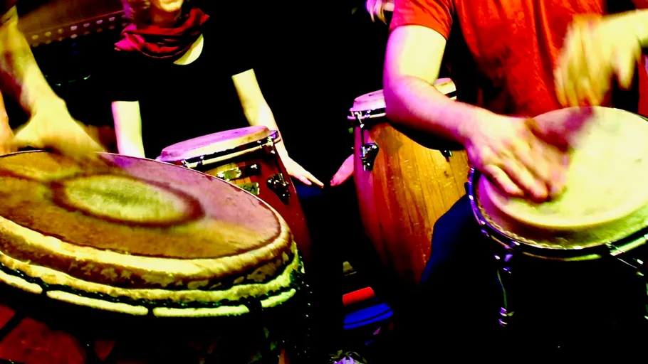 Menschen spielen Trommeln in lebhafter Umgebung.