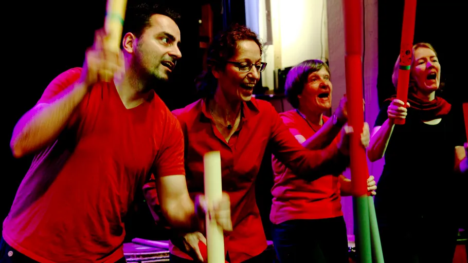 People in red shirts playing percussion instruments.
