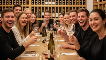 Group of people laughing at dinner table.