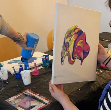 Person holding canvas with abstract paint art.