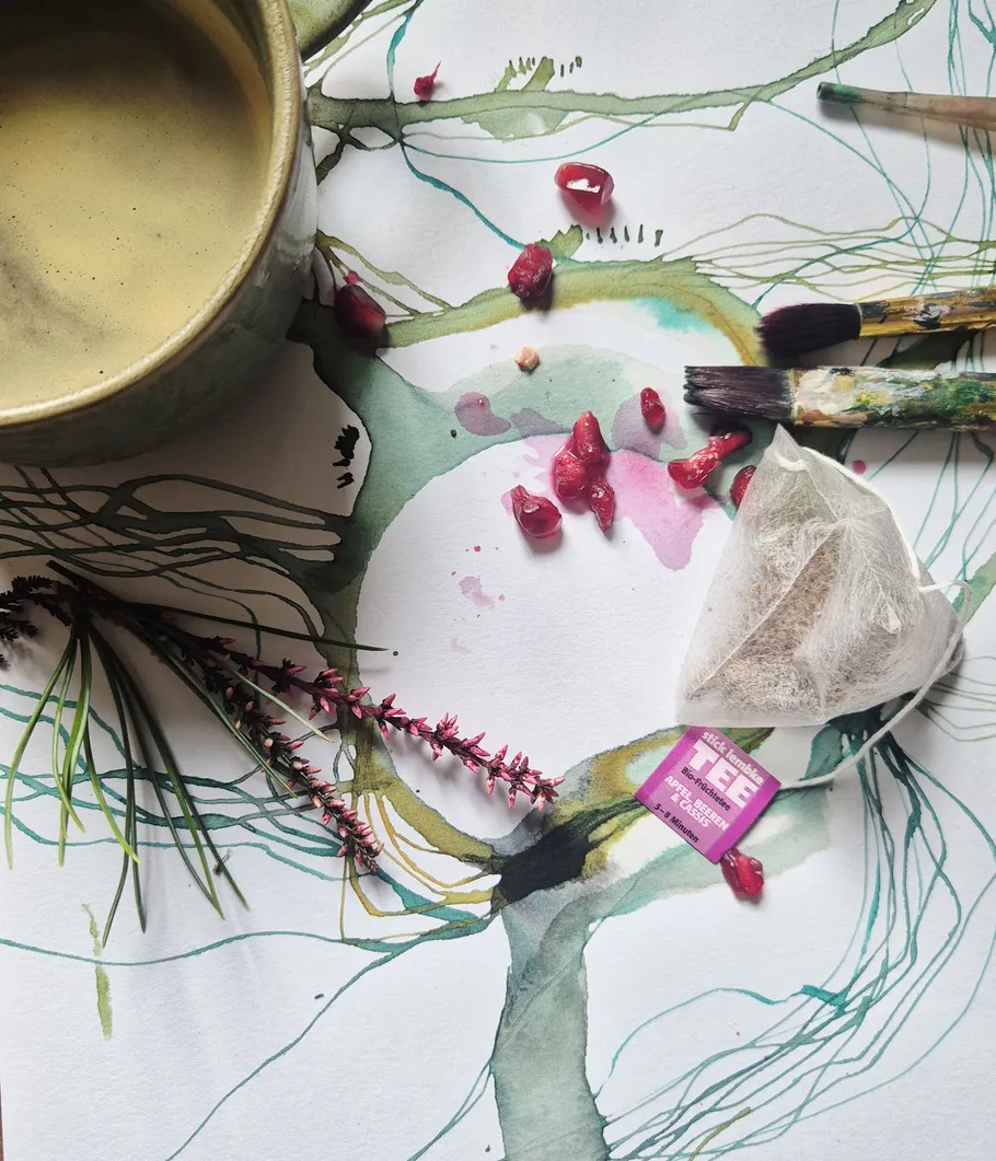 Cup and paintbrushes on abstract watercolor painting.