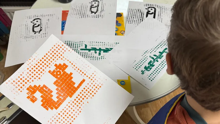 Child observing pixel art on printed sheets.