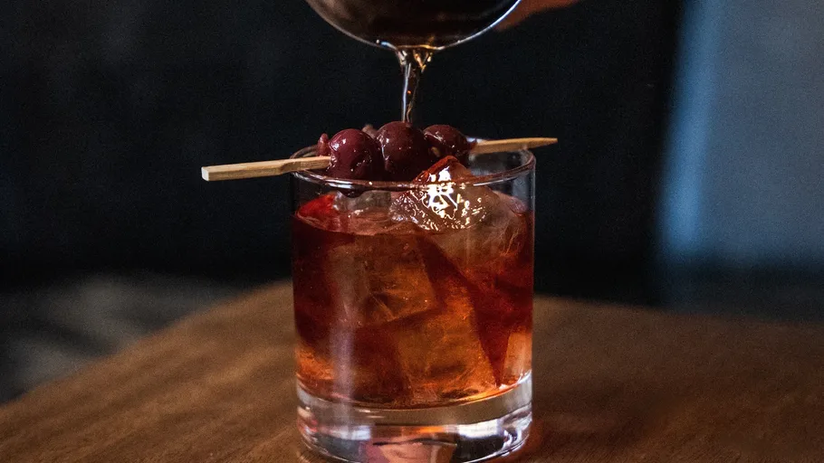 Cocktail being poured with cherries garnish.