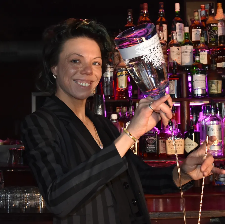 Woman pouring drink behind a bar.