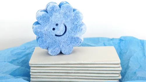 Blauer Blütenschwamm lächelt auf Fliesen.