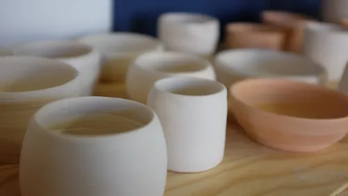 Unfertige Töpferbecher auf einem Holztisch.