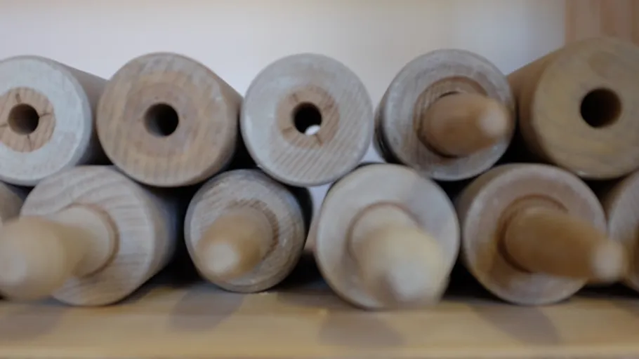 Rolling pins stacked on a wooden shelf.