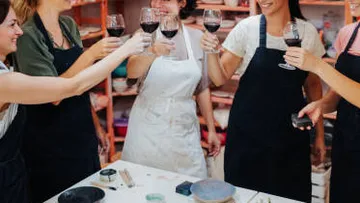 Gruppe von Personen stößt mit Wein in Schürzen an.