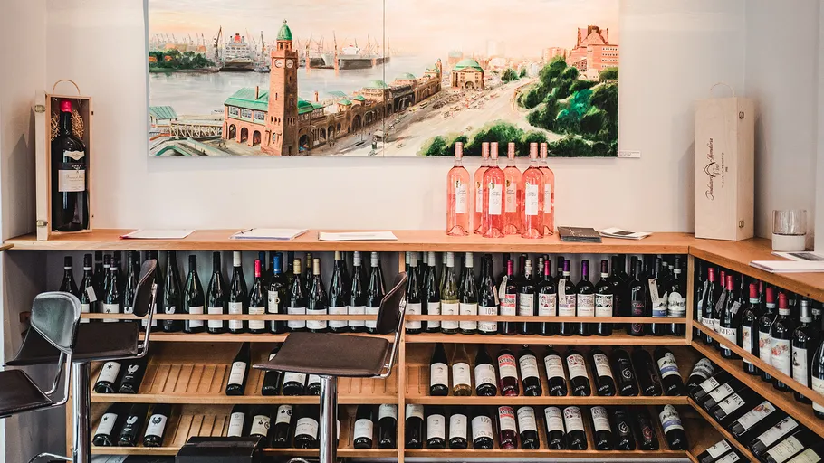 Wine bottles displayed under bar with artwork above.