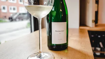 Weinglas und Flasche auf Holztisch.