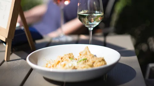 Pasta dish and wine on outdoor table.