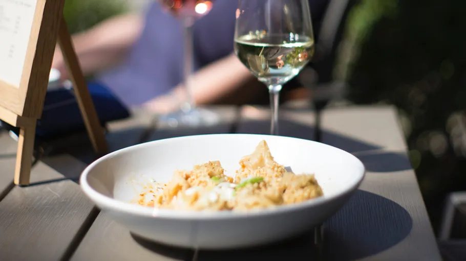 Pasta dish and wine on outdoor table.