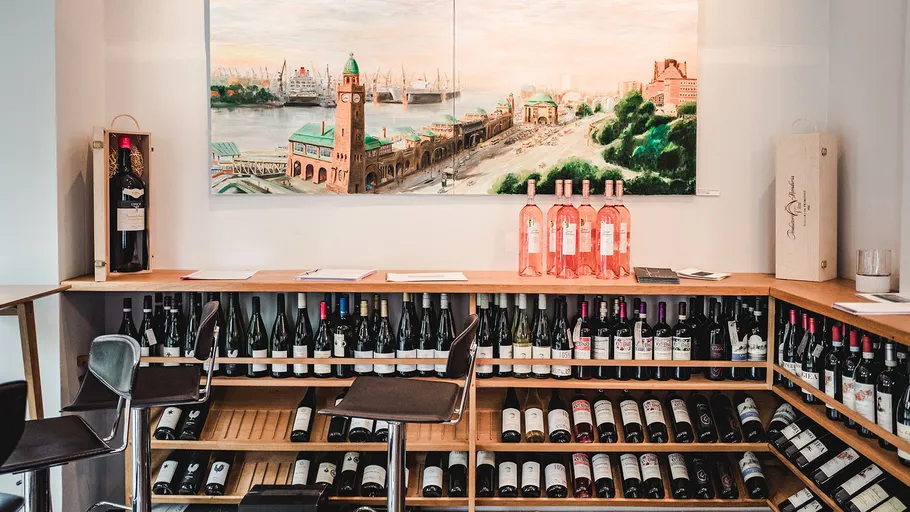 Wine bottles displayed under a scenic painting.