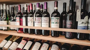 Wine bottles displayed on wooden shelf.