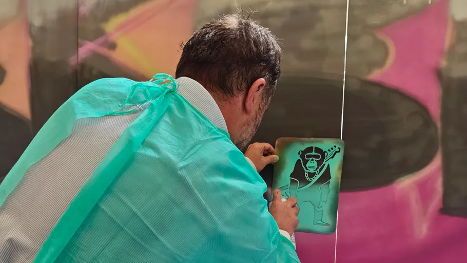 Person sprüht Schablone an eine Wand.