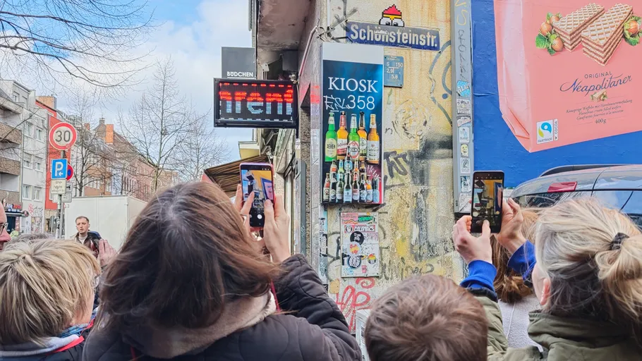 People taking photos of street corner kiosk.