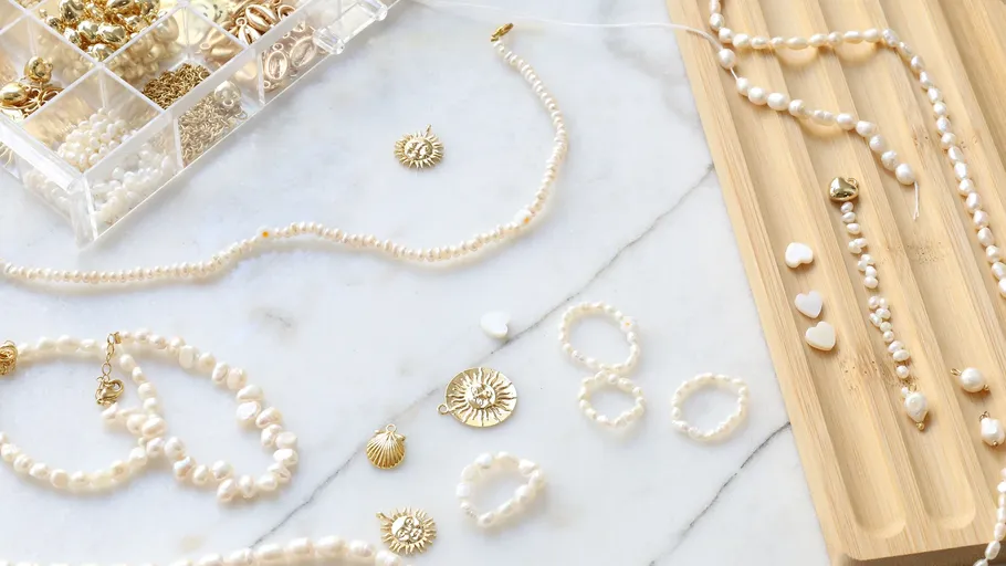 Schmuck mit Perlen und Goldanhängern auf einem Tisch.
