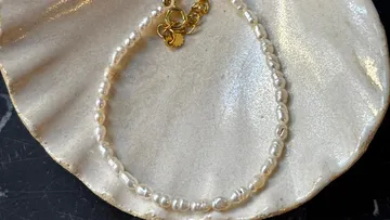 Pearl necklace with gold clasps on shell.