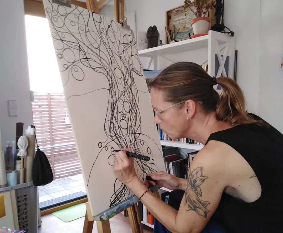 Woman drawing abstract lines on canvas indoors.