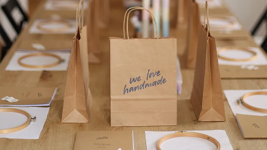 Paper bags and embroidery kits on wooden table.