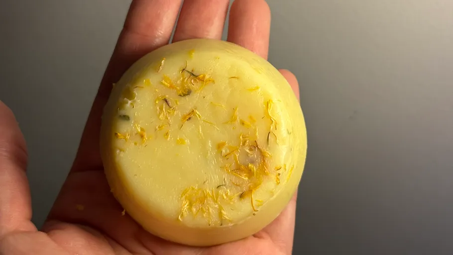 Round soap bar with dried flowers in hand.