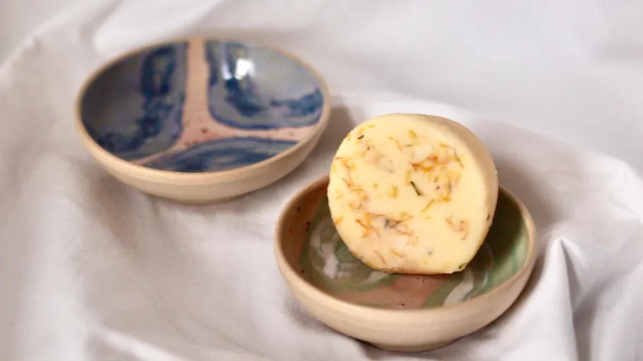 Round soap on ceramic dish, white background.