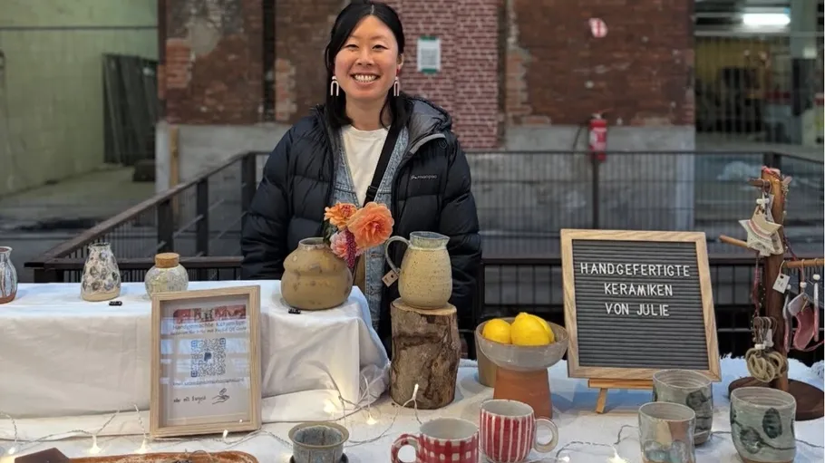 Woman smiling behind ceramic display table.