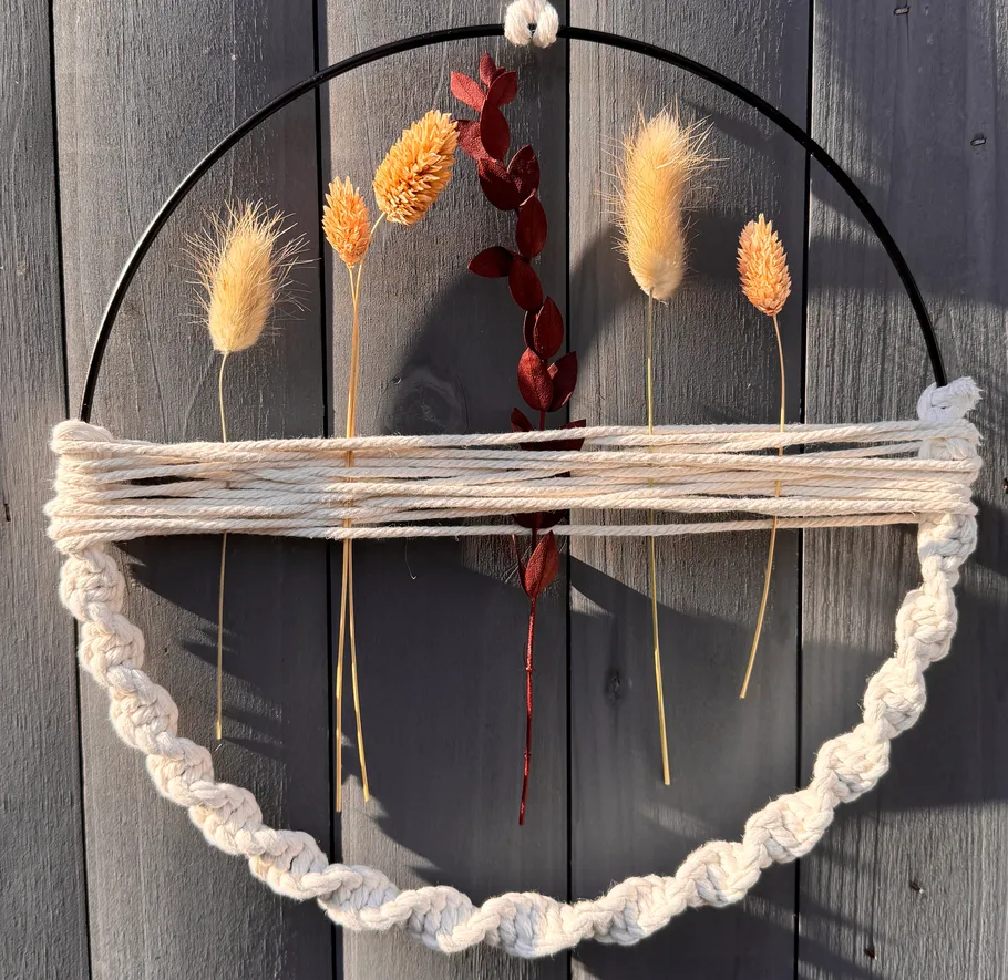 Decorative hoop with dried plants on wall.