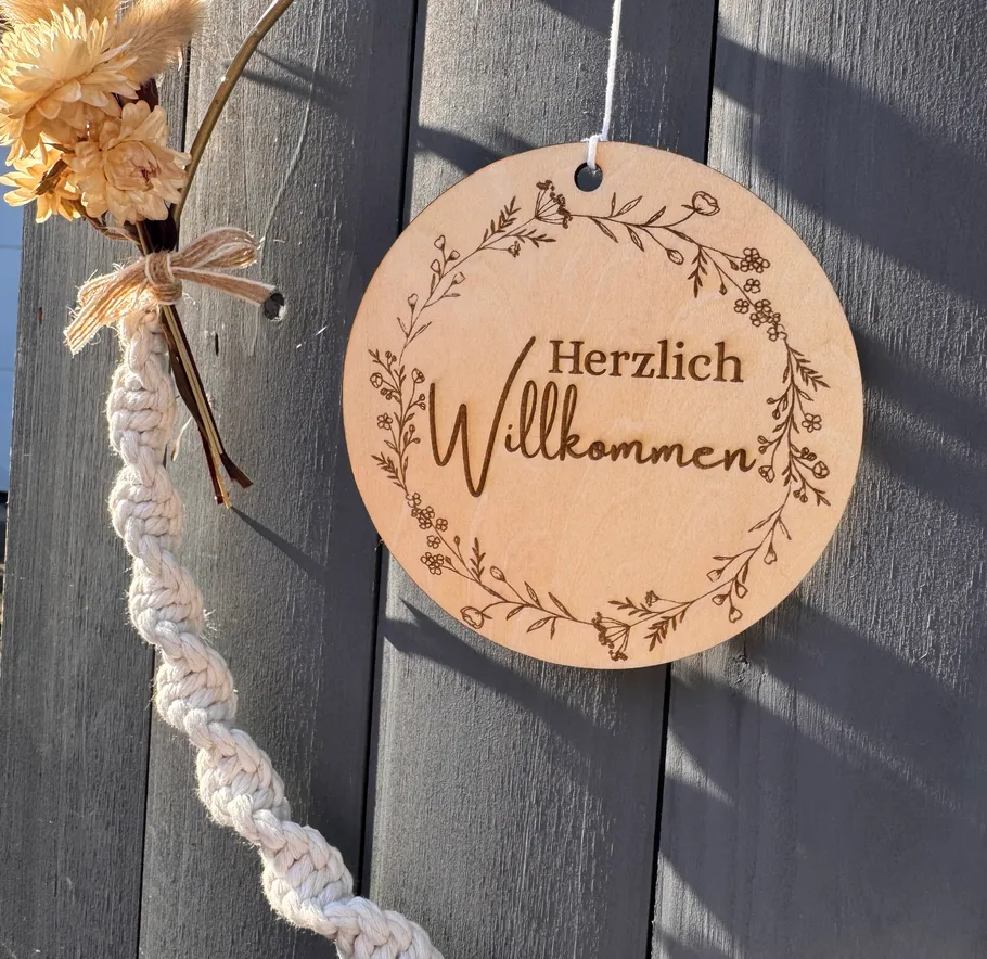 Willkommensschild an Holzzaun hängend.