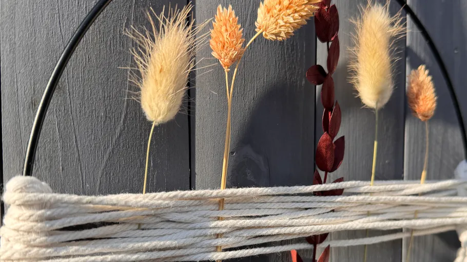 Dried flowers and strings on wooden wall.
