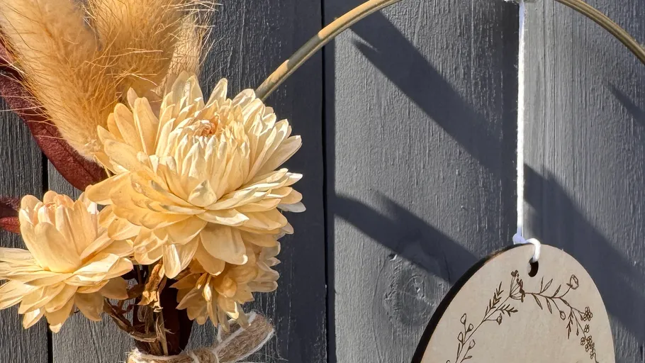 Blumenstrauß mit rundem Schild auf Holz.