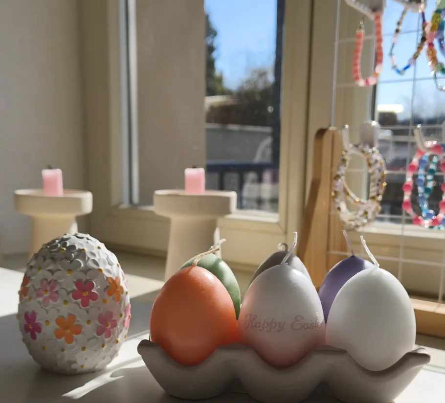 Dekorative Kerzen und Schmuck am sonnigen Fenster.