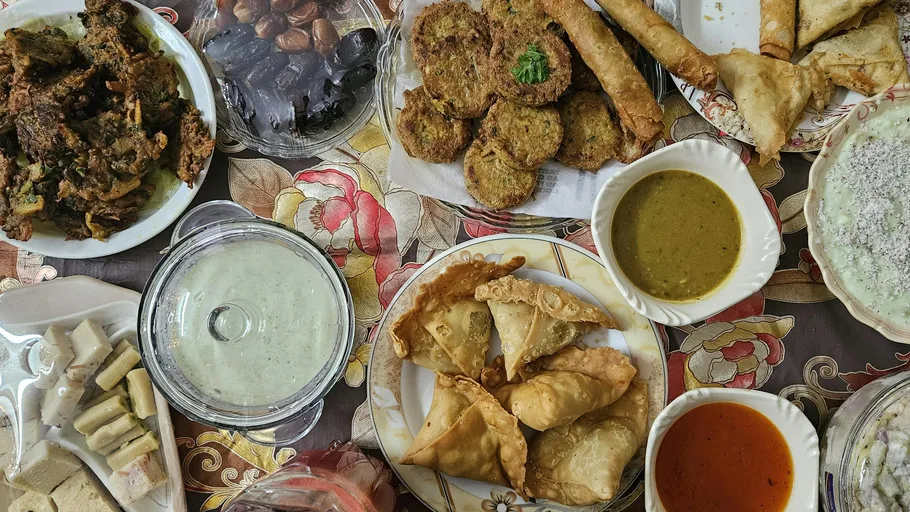 Various fried snacks and sauces on floral tablecloth.