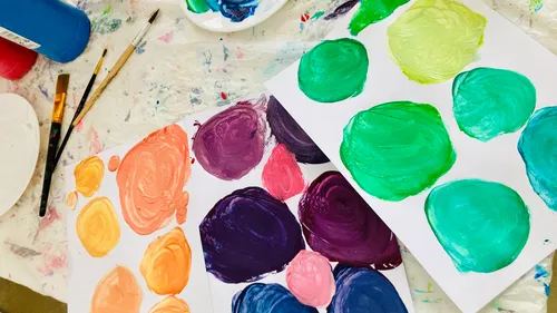 Colorful paint circles on messy paper surface.