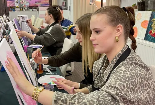 Frauen malen auf Leinwänden in einem Kunstkurs.