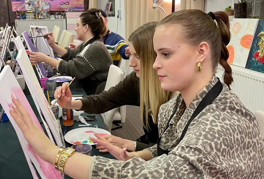 Women painting on canvases in an art class.