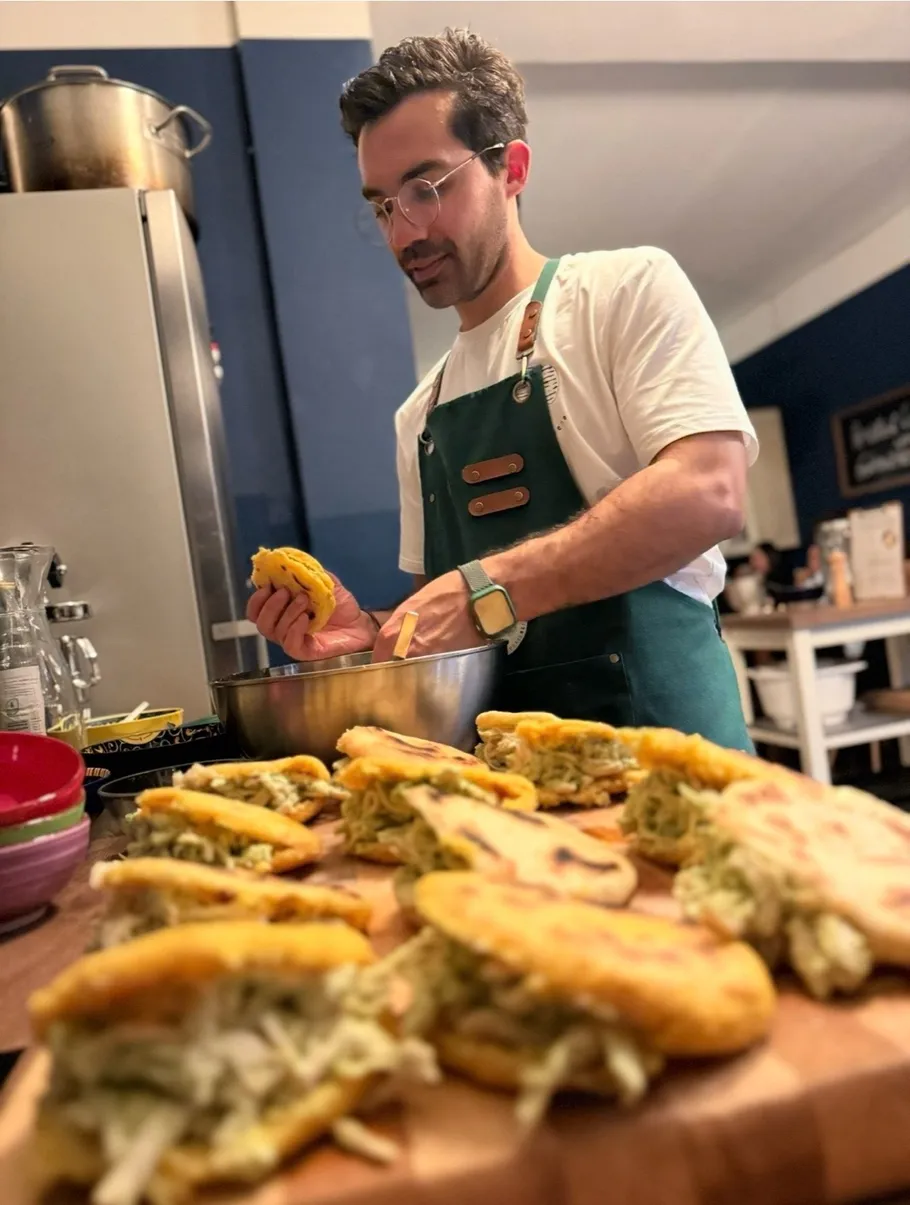 Man preparing arepas in a kitchen environment.