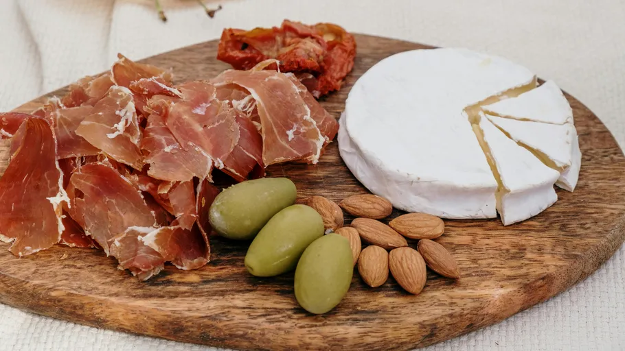 Charcuterie board with cheese, ham, and olives.