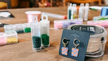 Earrings on display surrounded by beading materials.