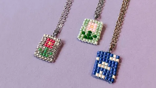 Three beaded pendants on chains, purple background.