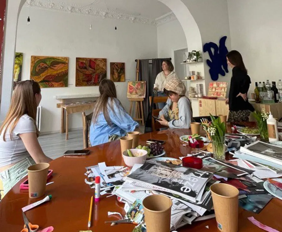 People in art studio discussing artworks on walls.