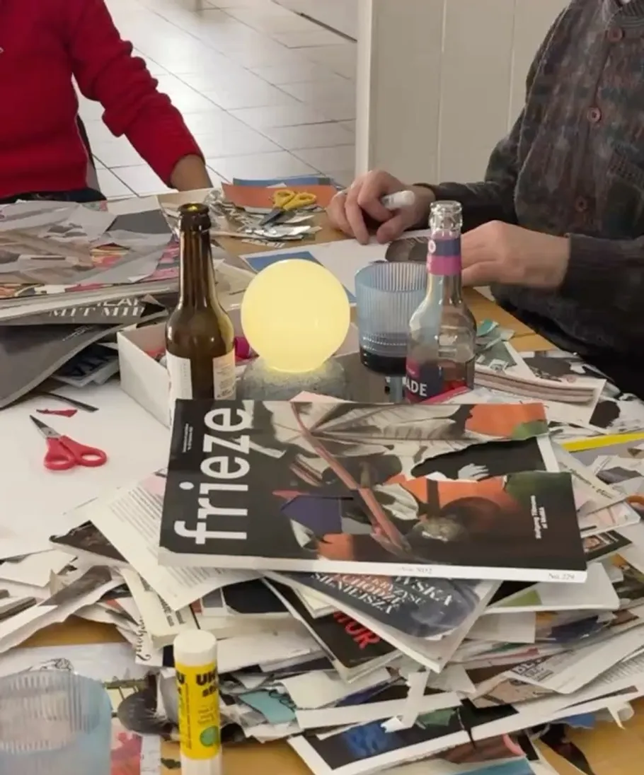 People crafting at a cluttered table indoors.