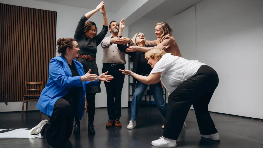 Group of people practicing theater in a room.