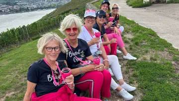 Gruppe Frauen sitzt, hält pinke Becher.