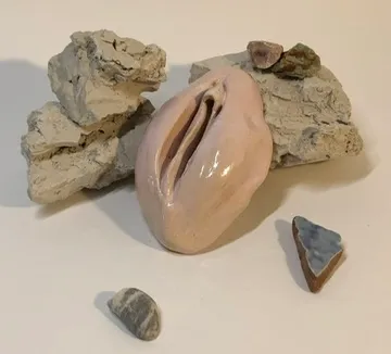 Keramikskulptur mit Steinen auf weißem Hintergrund.