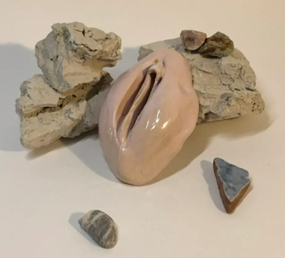 Keramikskulptur mit Steinen auf weißem Hintergrund.