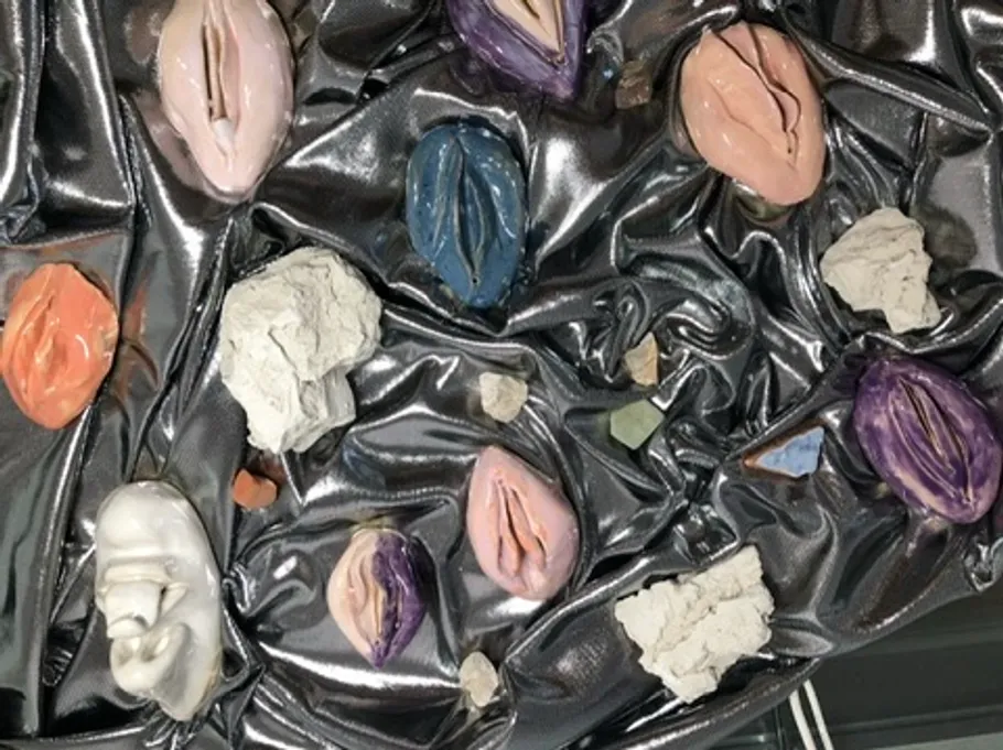 Colorful clay sculptures on metallic fabric background.