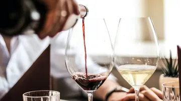 Rotwein wird in Gläser im Esszimmer eingeschenkt.